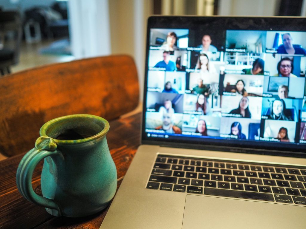 A laptop showing a video call with many participants