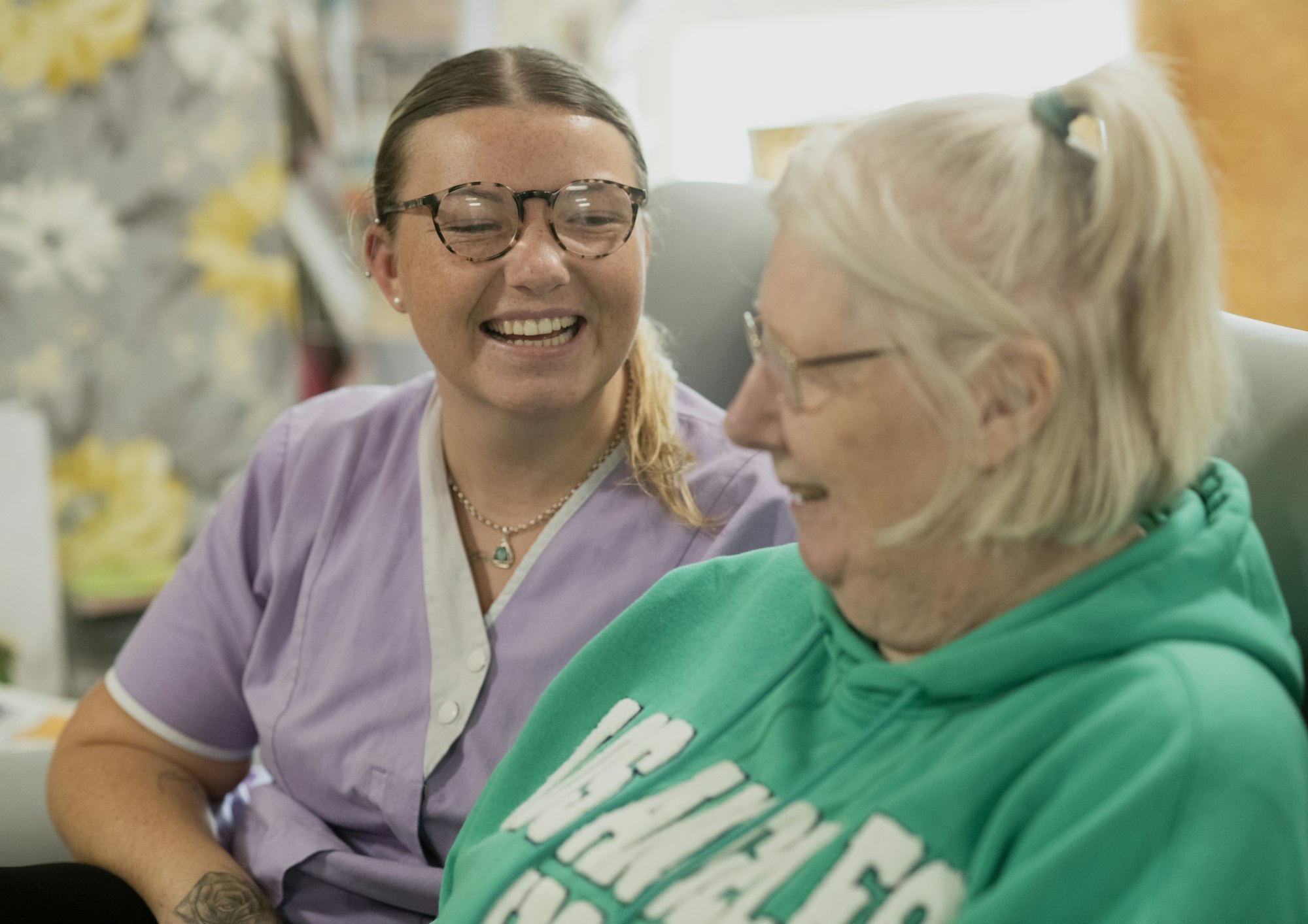 A carer and a care home resident laughing together