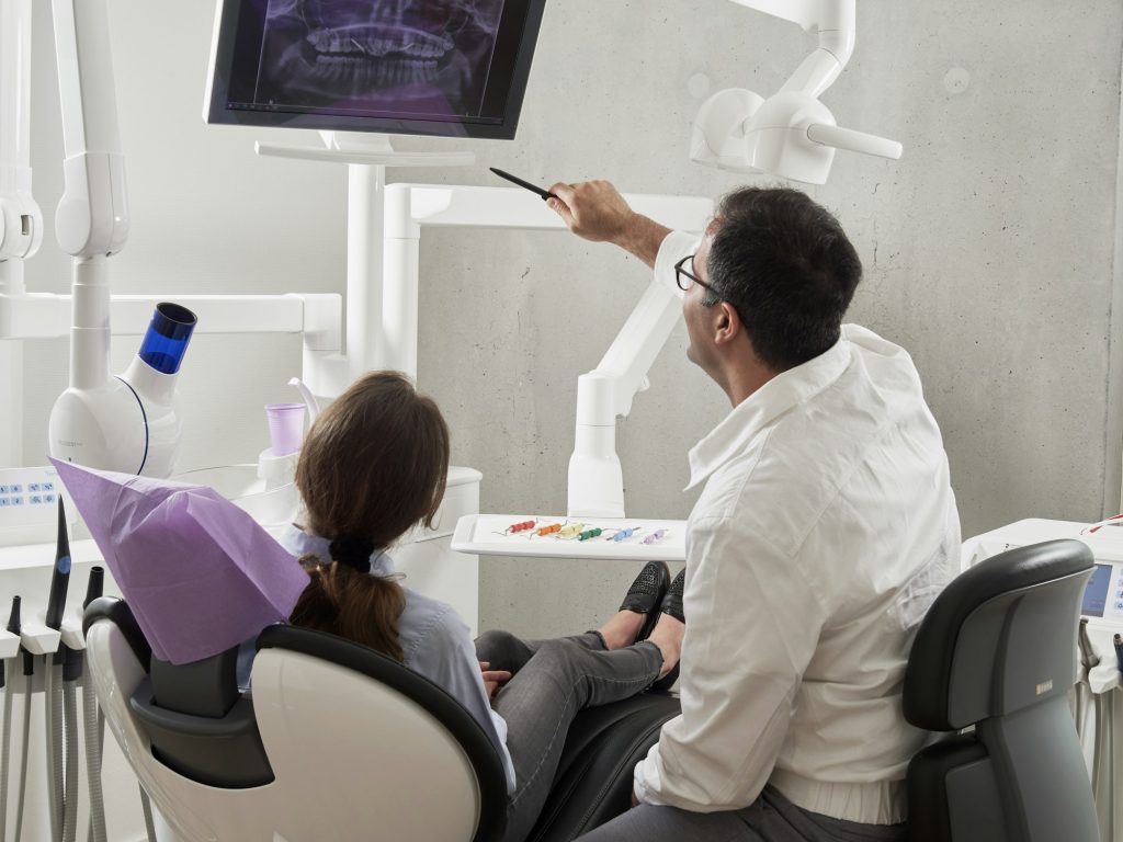 A dentist talking a patient through an X-ray in a dental practice